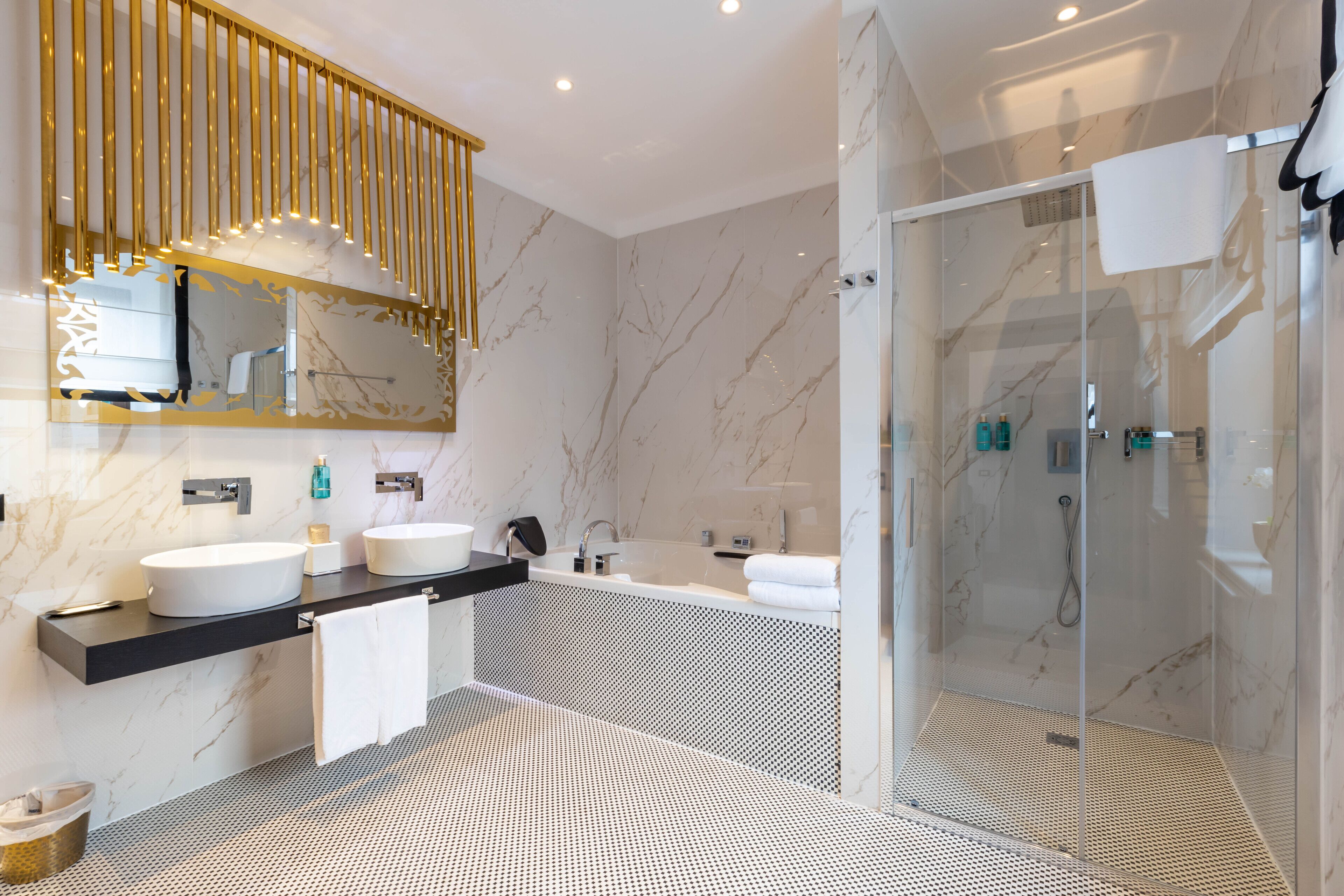Une salle de bain moderne avec deux lavabos, une douche à parois de verre et un carrelage décoratif.