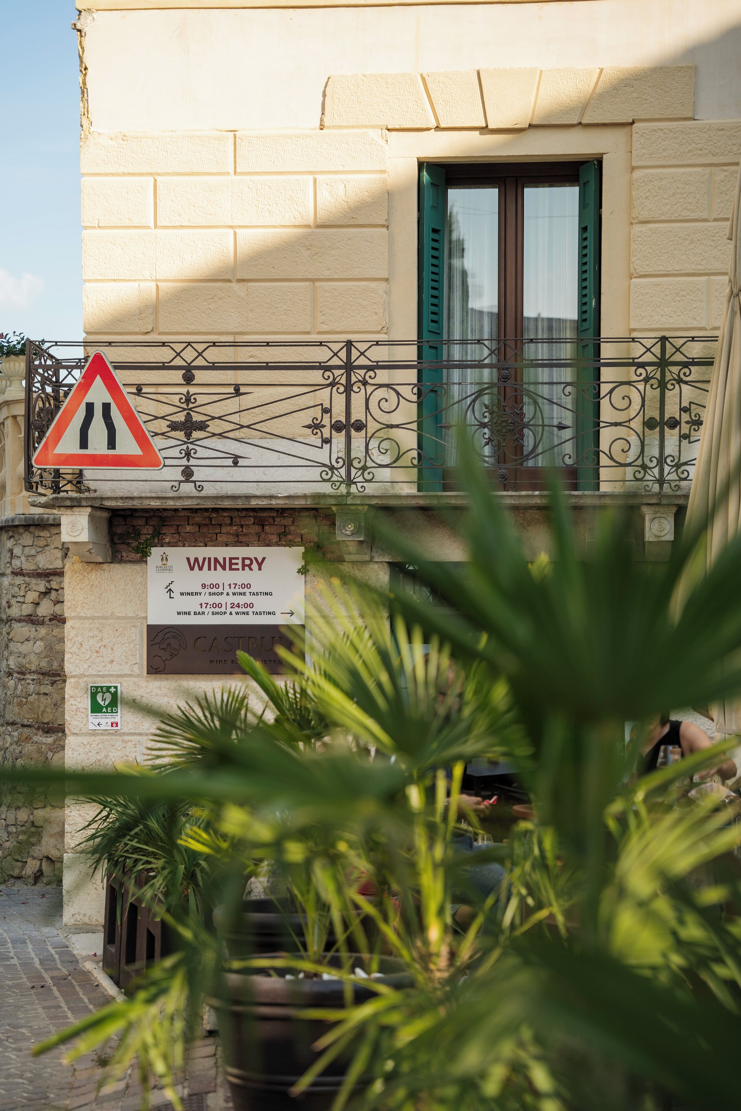 Ein Gebäude mit einem Schild für ein Weingut, eine enge Straße und ein dreieckiges Warnschild.