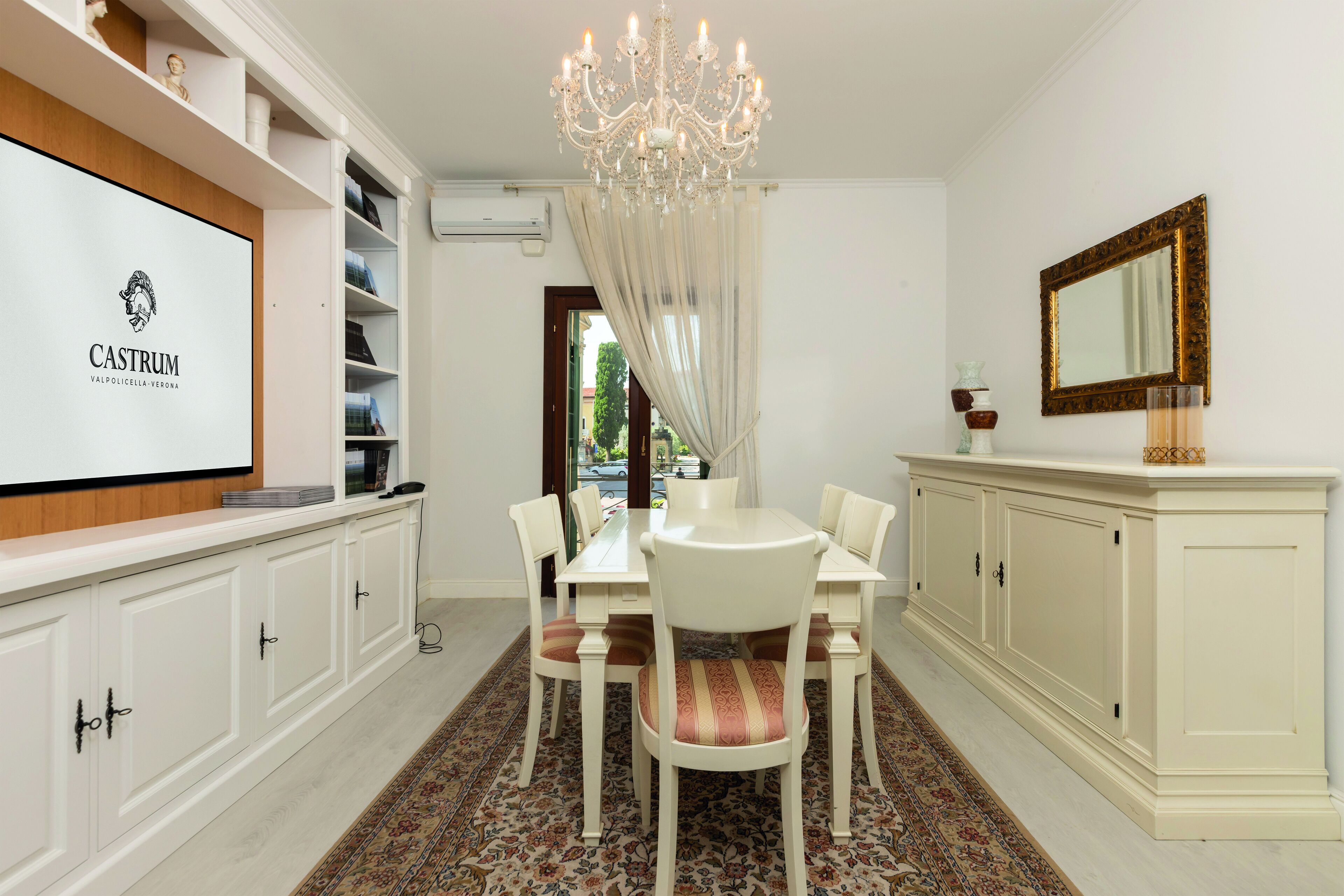 A dining area with a chandelier, white cabinets, and a table set for six.