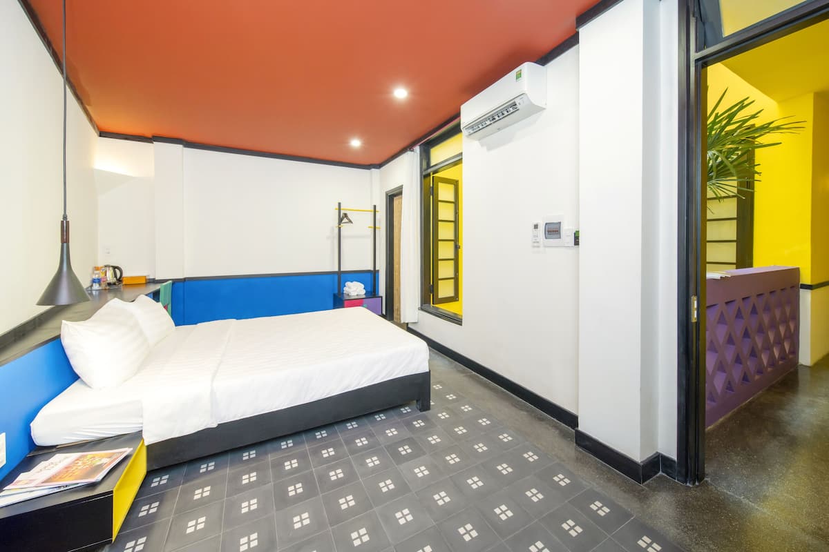 Una habitación de hotel con una cama, un escritorio, una lámpara y una ventana.