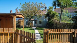 A wooden gate leading to a pathway, a small wooden structure, and a house with a tiled roof. - Pet friendly, comfortable family home with sea views near the Giant's Causeway (Bushmills)