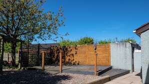 A fenced outdoor area with a wooden gate, a paved walkway, and a small step leading to a building. - Pet friendly, comfortable family home with sea views near the Giant's Causeway (Bushmills)