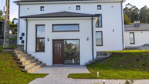 Een modern huis met twee verdiepingen, een voordeur, stenen trappen en een verharde oprit.