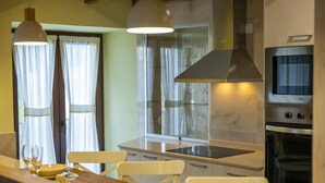 Een moderne keuken met een centraal eiland, roestvrijstalen apparatuur en een eethoek met witte stoelen.