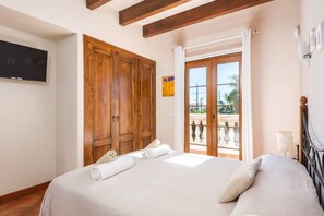 Ein Schlafzimmer mit Bett, Holzschrank und Balkon mit Blick.