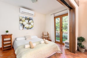 Et soveværelse med en seng, en stol, en potteplante og en skydedør, der fører ud til en balkon.