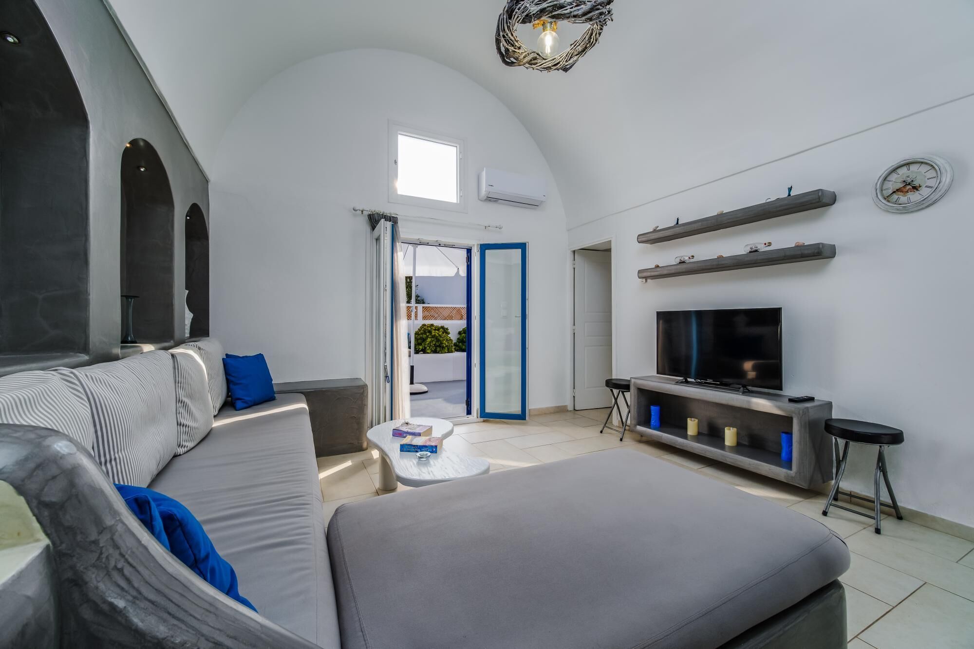 Ein modernes Wohnzimmer mit grauem Sofa, Flachbildfernseher und Kamin.