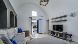 A modern living room with a grey sofa, a flat-screen TV, and a fireplace. - Casa Maritina Private Villa With Jacuzzi (Santorini)