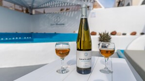 A bottle of Santorini wine and two glasses on a white table by a pool. - Casa Maritina Private Villa With Jacuzzi (Santorini)