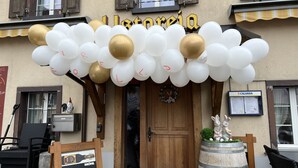 A building entrance with a sign reading "Lorenzo," decorated with white and gold balloons. - Gasthaus Alpina Salouf (Surses)