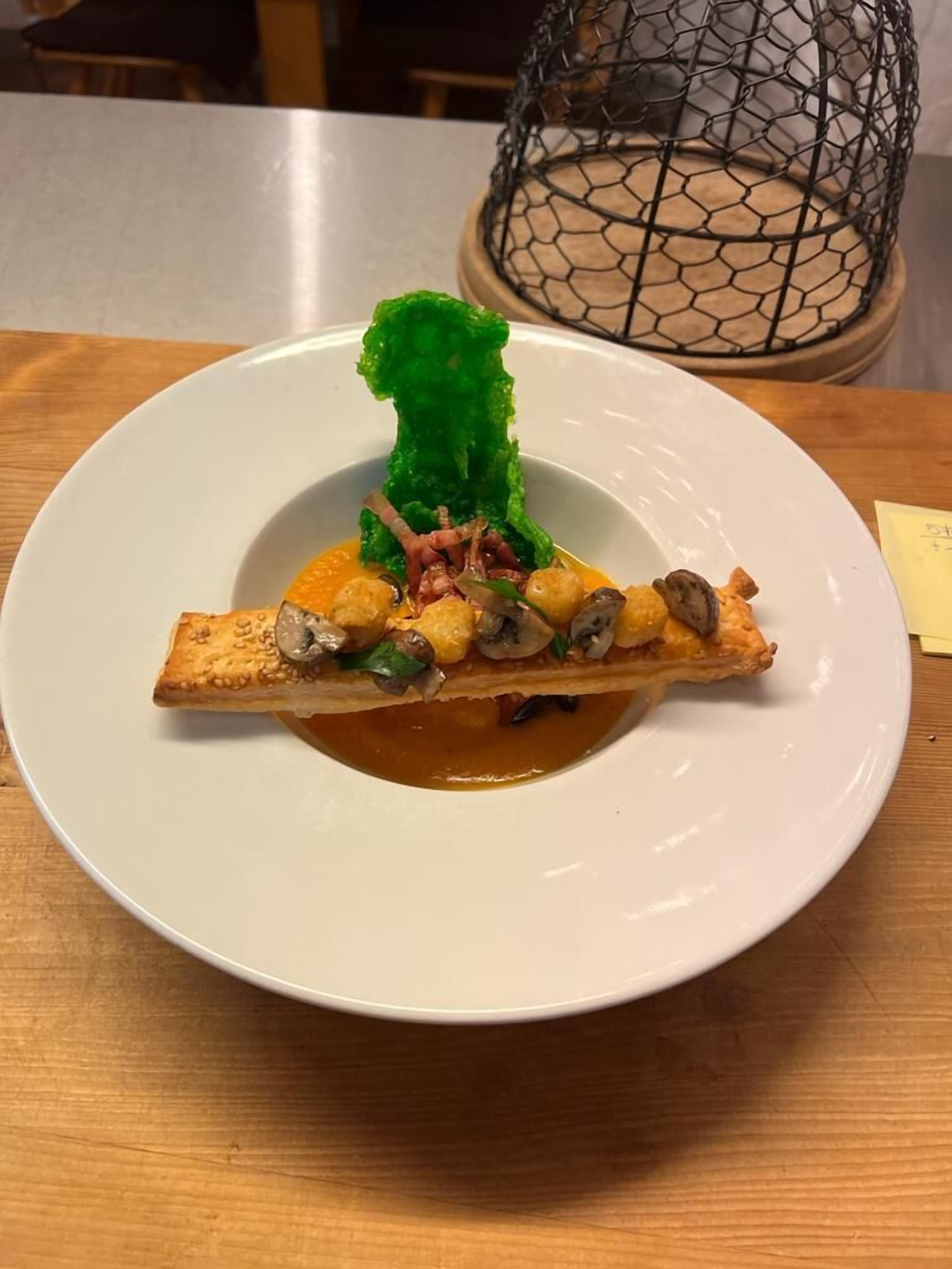 Une assiette de nourriture comprenant une tranche de pain garnie de champignons et de légumes verts, le tout servi dans une assiette blanche.