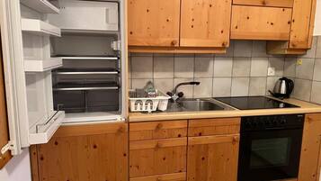 A kitchen with wooden cabinets, a built-in oven, a sink, and a window with a view of the outside.