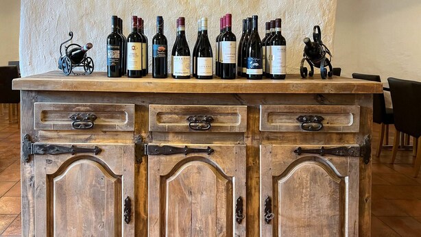 A wooden bar with multiple wine bottles and a small decorative item. - Gasthaus Alpina Salouf (Surses)