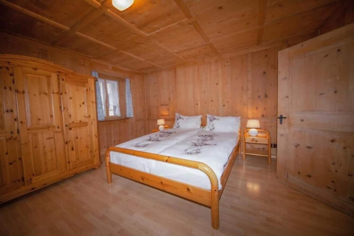 A wooden room with a bed, two nightstands, and a wardrobe.