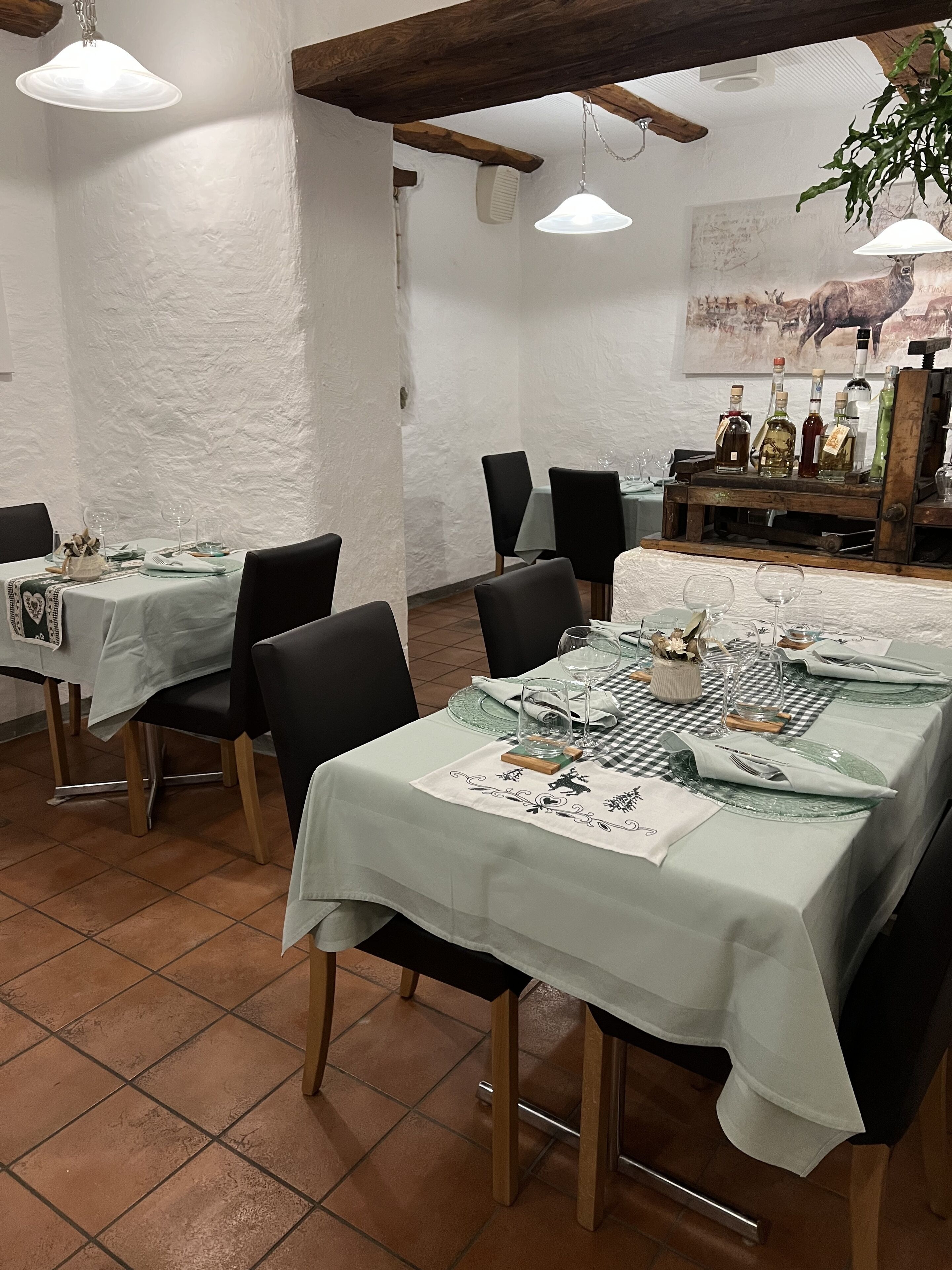 Un espace repas avec des tables préparées pour deux personnes, agrémenté de nappes blanches et de chaises noires.