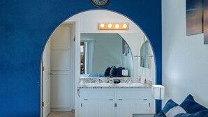 Ein Badezimmer mit einem großen Spiegel, einem Waschtisch mit zwei Becken und einer Uhr an der Wand.