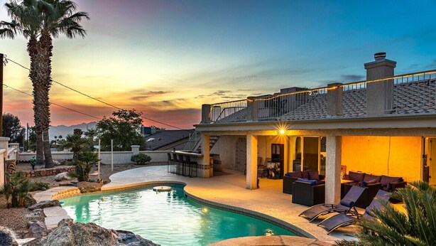 Ein Schwimmbecken mit Liegestühlen und einer überdachten Terrasse.