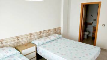 Un dormitorio con dos camas individuales, cabecero de madera, mesita de noche y lámpara colgante.