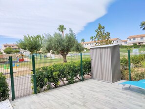A fenced outdoor area with a wooden deck, a small shed, and a playground with colorful equipment. - Resort Home 10 (castellon)