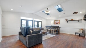 Un salon spacieux avec un canapé gris, un plancher en bois et une cheminée.