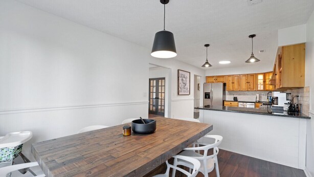 Une cuisine moderne avec des meubles en bois, un grand îlot central et des luminaires suspendus.