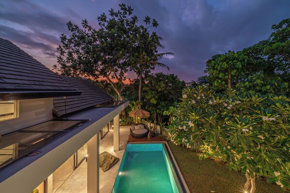 A modern house with a swimming pool, a covered seating area, and lush greenery. - Villa Prana (Kerobokan)