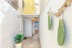 A narrow hallway with a potted plant, a drying rack, and a wooden beam.