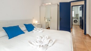 A hotel room with a bed, blue pillows, a wardrobe, and a visible laundry area.