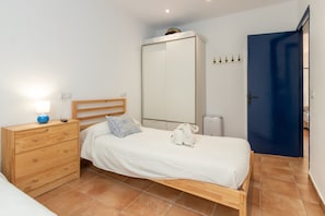 Un dormitorio con una cama de madera, una mesita de noche con lámpara, un armario y una puerta azul.