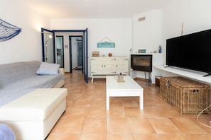Una sala de estar con sofá, mesa de centro, televisor, mueble y cesta de mimbre.