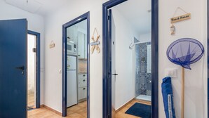 A hallway with a blue door, a welcome sign, a beach house sign, and a blue fan on the wall.