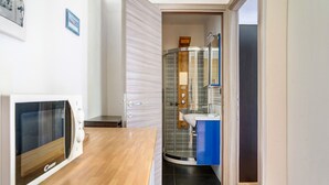 Una cocina con microondas, encimera de madera y cabina de ducha de vidrio con mueble azul.