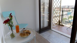 Ein Balkon mit Tisch, einer Blumenvase und einem Tablett mit Croissants.