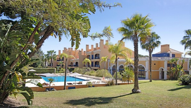 A hotel with a swimming pool, palm trees, and a courtyard. - Apartment "T2 Vilasol" with Shared Pool & Wi-Fi (Vilamoura)