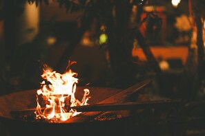 A campfire with logs and flames, surrounded by a dark environment. - Dalat Blue House Homestay & Cafe (Lam Vien - Da Lat)