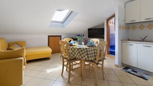 Un espacio habitable compacto con comedor, sofá, cocina y tragaluz.