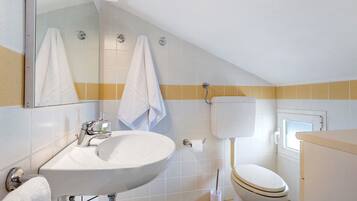 Une salle de bain avec un lavabo blanc, des toilettes et un miroir au-dessus du lavabo.