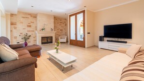 A modern living room with a fireplace, sofa, TV, and a coffee table.