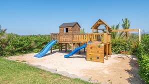 A wooden play structure with slides and climbing elements.