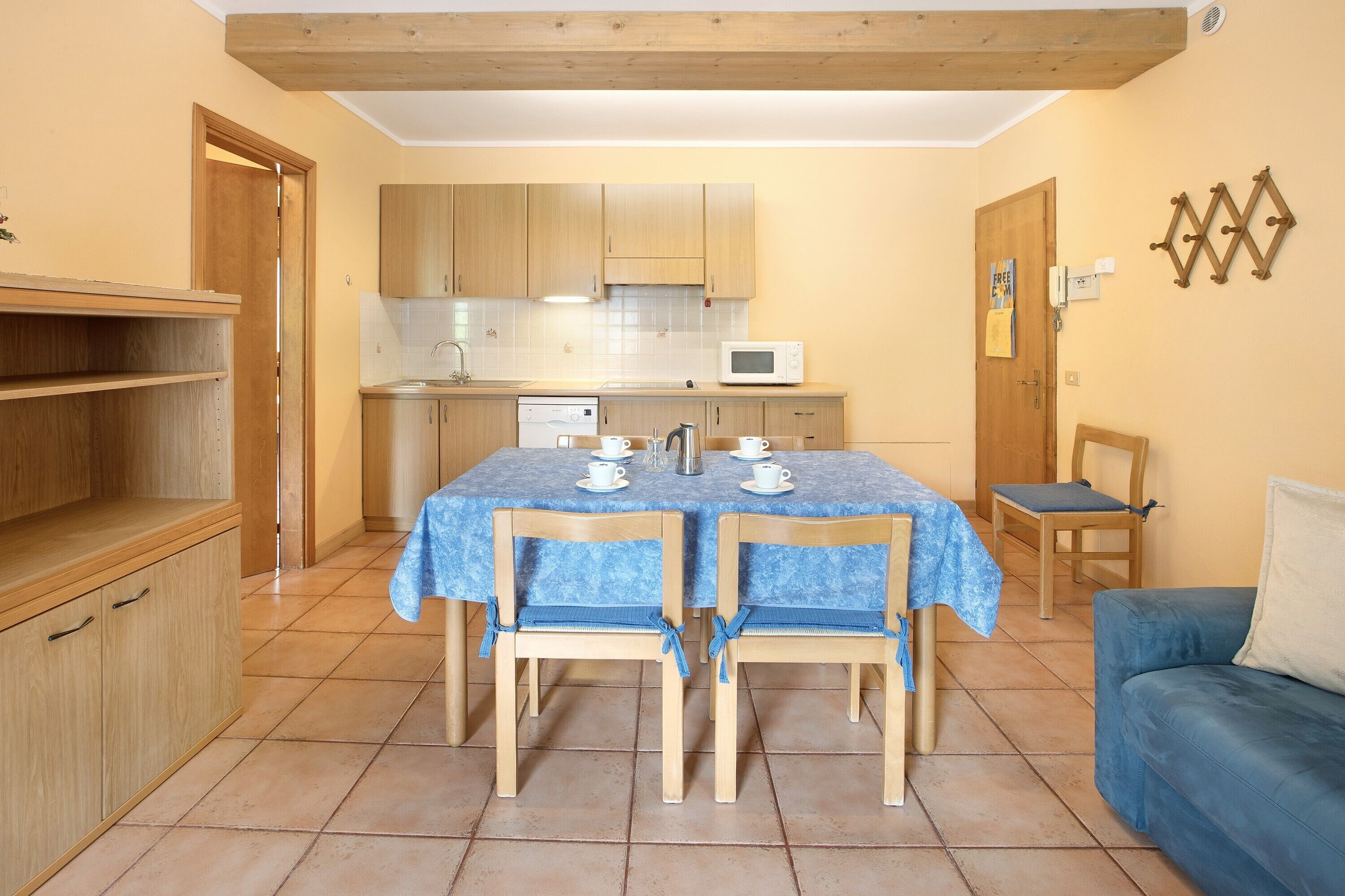 Une cuisine de taille réduite, dotée de meubles en bois, d’un four à micro-ondes et d’une table à manger avec des chaises.