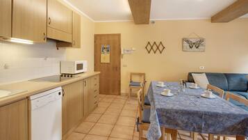A kitchen with wooden cabinets, a dishwasher, a microwave, and a dining area with a table set for two.