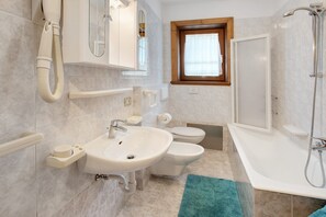 A bathroom with a sink, toilet, bidet, and bathtub.