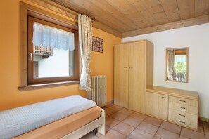 A bedroom with a bed, a wardrobe, a radiator, and a window with curtains.