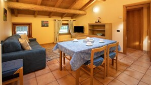 Un salon confortable avec un canapé, une table à manger et des chaises, un téléviseur et un plafond en bois.