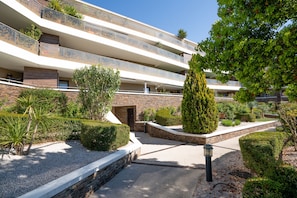 Un hôtel à plusieurs étages doté de balcons, d’un jardin aménagé et offrant une vue sur un ciel dégagé.