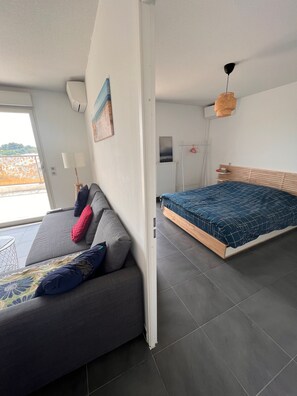 Une chambre moderne équipée d’un canapé, d’un lit, d’un radiateur et d’un ventilateur de plafond.
