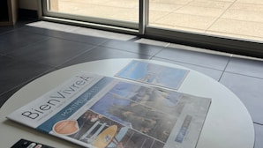 A room with a large window, a remote control, and a magazine on a table. - Apartment 'T2 Muses' with Private Terrace, Wi-Fi and Air Conditioning (Le Crès)