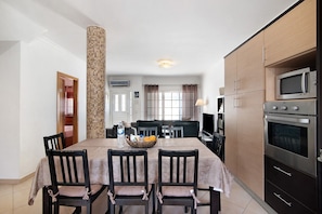 A dining area with a table set for four, a microwave, and a stove in the kitchen area.