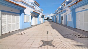 Una calle con edificios de fachadas azules y blancas, un pavimento con marca en forma de estrella y persianas cerradas.