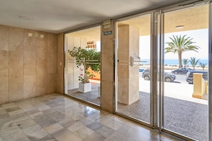 Een hotel lobby met een marmeren vloer, een grote glazen deur die naar buiten leidt en een bord met de aanduiding van de uitgang.